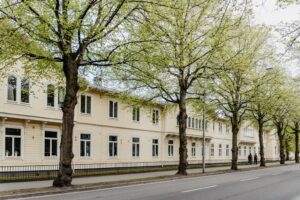 Lång gul trävilla med stora fönster och träd längs Barnarpsgatan 39.