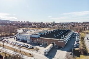 Stor industribyggnad med kontorsdel vid Thulevägen 2 i Huskvarna, sedd från luften.
