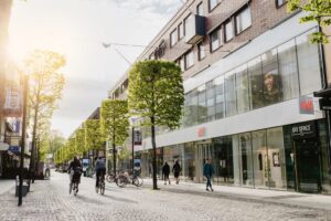 Solig gågata vid Bredgränd 5 med butiker och cyklister i Jönköping.